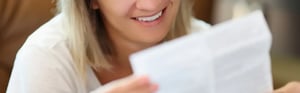 Eine lächelnde Frau liest eine Gebrauchsanweisung (IFU) für ein Medizinprodukt im Kontext der klinischen Bewertung.