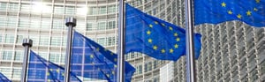 EU flags in front of a European Union building, symbolizing the EU proposal on the MDR, IVDR, EUDAMED, and new transitional provisions for medical devices