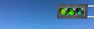 Grüne Ampel vor blauem Himmel – Symbol für die positive Bewertung und Gewichtung klinischer Daten bei der klinischen Bewertung von Medizinprodukten.
