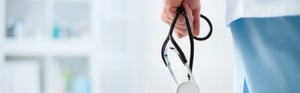 Eine Person aus dem medizinischen Bereich hält ein Stethoskop, symbolisch für klinische Praxis und medizinische Forschung im Krankenhausumfeld.
